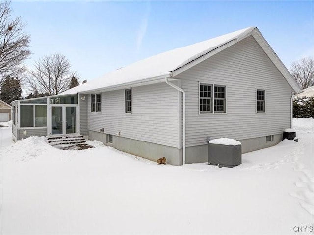 snow covered back of property with a sunroom