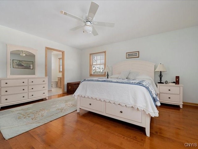 bedroom with ceiling fan, ensuite bath, and wood finished floors