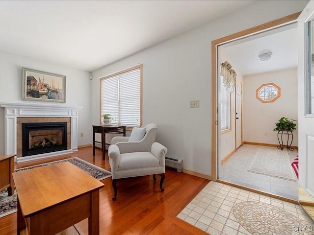 living area featuring light wood-type flooring, a baseboard radiator, a fireplace, and baseboards