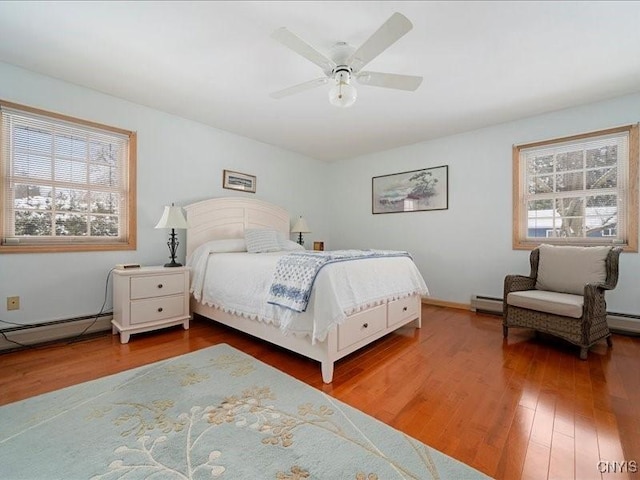 bedroom featuring a baseboard radiator, multiple windows, and wood finished floors