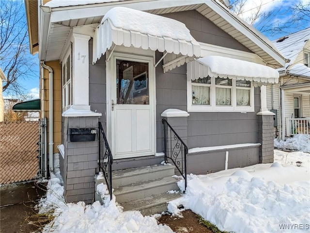 snow covered property entrance with a garage and fence