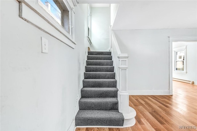 stairway with baseboards, baseboard heating, and wood finished floors