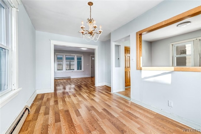 unfurnished dining area with baseboards, light wood finished floors, baseboard heating, and an inviting chandelier