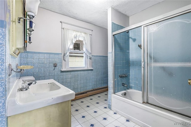 bathroom featuring tile walls, a baseboard heating unit, wainscoting, enclosed tub / shower combo, and a textured ceiling