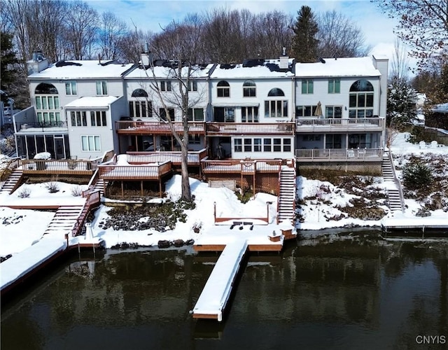 snow covered house featuring stairs and a water view