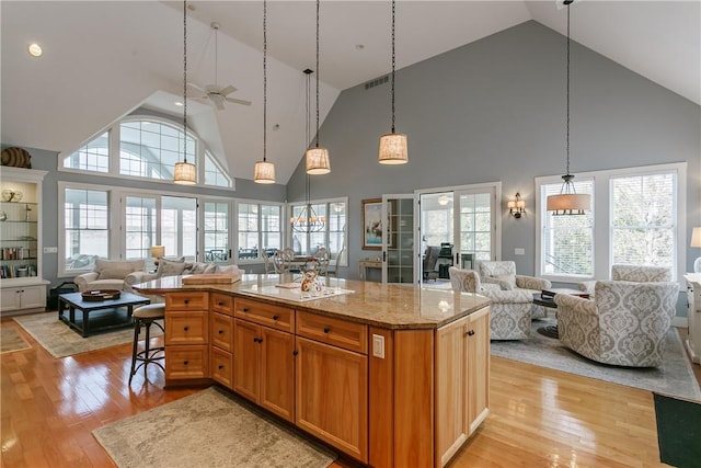 kitchen with open floor plan, light stone counters, light wood finished floors, and visible vents