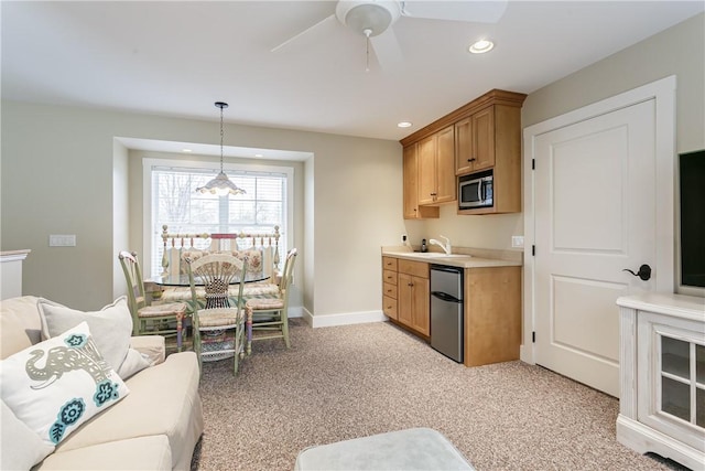 kitchen with recessed lighting, light countertops, stainless steel microwave, light carpet, and a sink