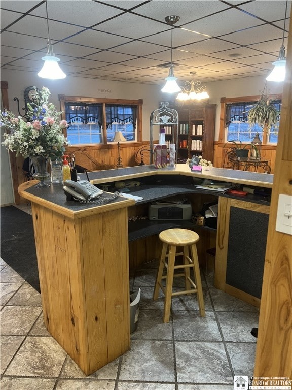 bar with a paneled ceiling, decorative light fixtures, wet bar, and stone tile floors