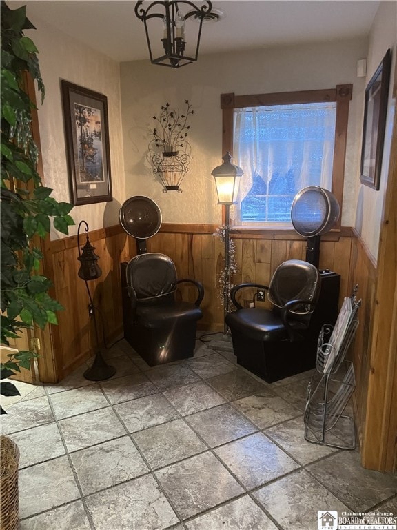 living area with a wainscoted wall, wood walls, and stone tile flooring