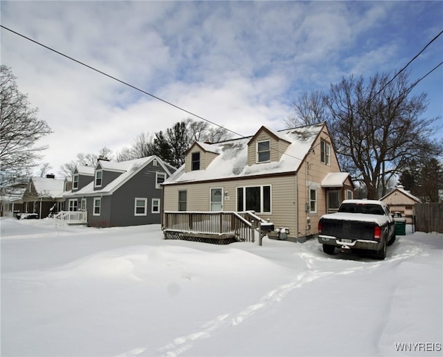 cape cod-style house featuring a detached garage and a deck