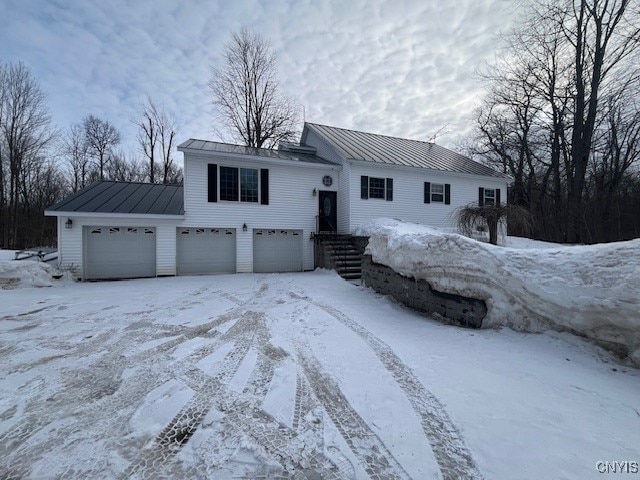 raised ranch featuring a standing seam roof, metal roof, and driveway