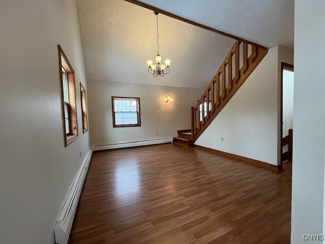 spare room with dark wood-style floors, stairs, baseboard heating, a textured ceiling, and a baseboard heating unit