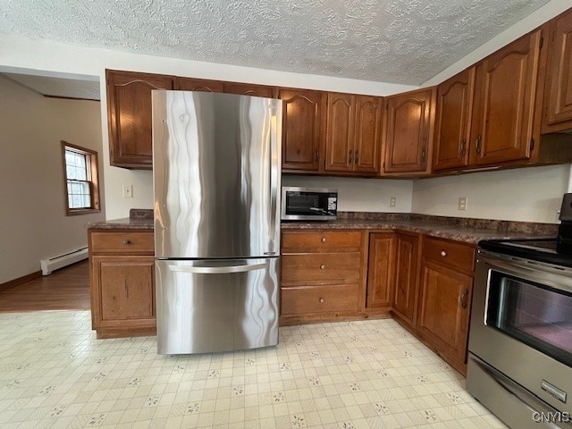 kitchen featuring light floors, stainless steel appliances, a baseboard radiator, dark countertops, and a textured ceiling