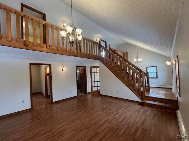 unfurnished living room with a notable chandelier, stairway, a baseboard heating unit, a textured ceiling, and wood finished floors