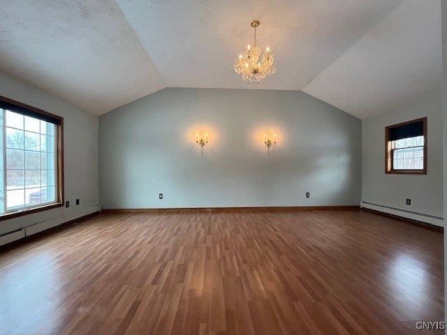 additional living space featuring an inviting chandelier, a baseboard radiator, vaulted ceiling, and wood finished floors