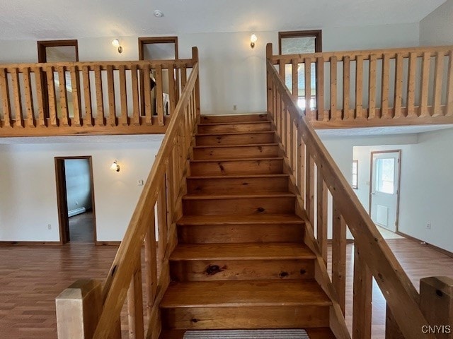 staircase with a high ceiling and wood finished floors