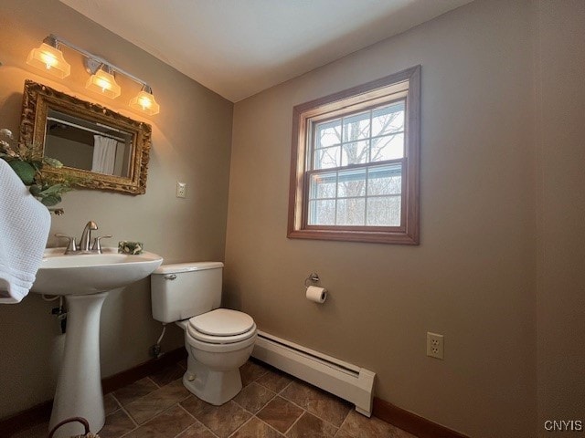 bathroom with baseboard heating, toilet, and baseboards