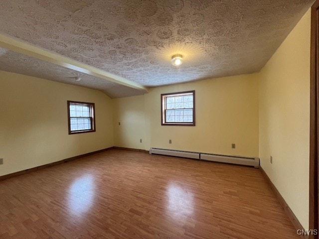 spare room with a baseboard radiator, a textured ceiling, baseboards, and wood finished floors