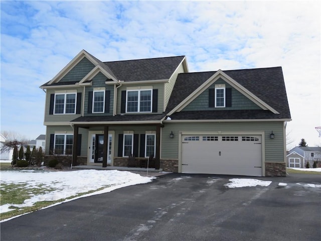 craftsman-style house featuring a garage, stone siding, and driveway