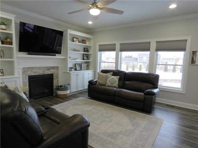 living room with dark wood-style flooring, a healthy amount of sunlight, crown molding, and a fireplace