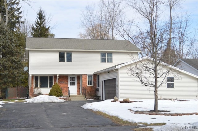 view of front of property featuring brick siding, driveway, and fence