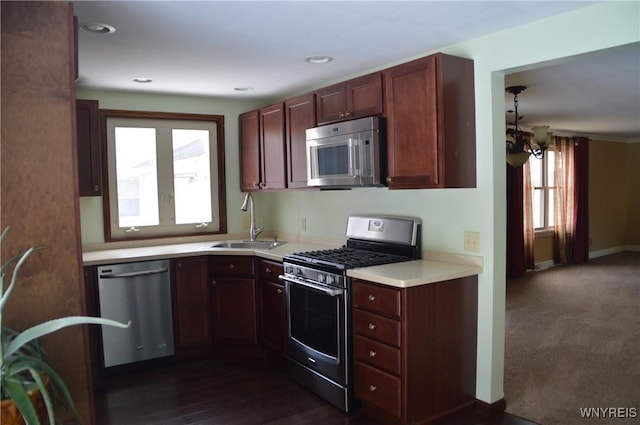 kitchen featuring baseboards, appliances with stainless steel finishes, light countertops, a chandelier, and a sink