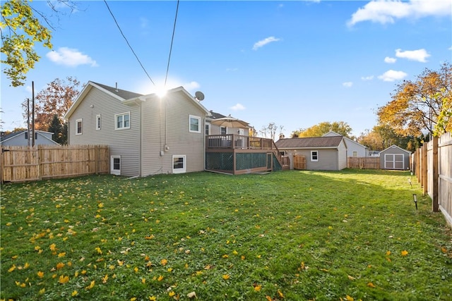 back of house with a fenced backyard, a storage unit, a lawn, and an outbuilding