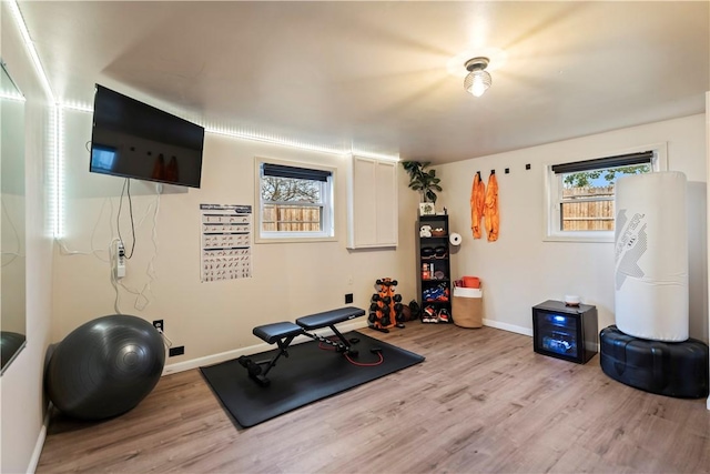 workout room with baseboards and light wood finished floors