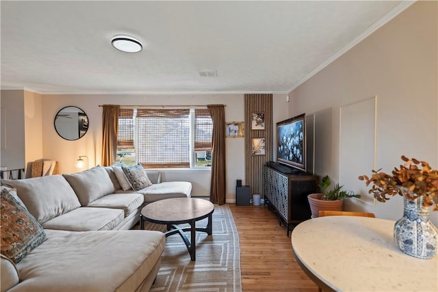 living room featuring crown molding, visible vents, and light wood-style floors