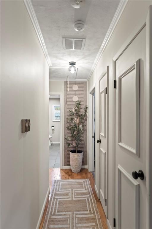 corridor featuring baseboards, visible vents, and crown molding