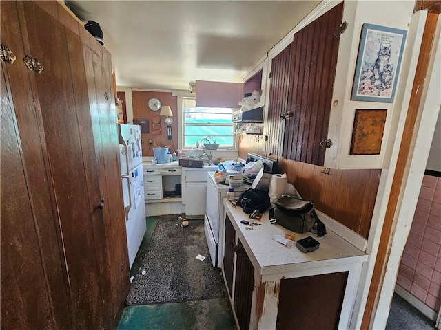 kitchen with light countertops, freestanding refrigerator, range, and wooden walls