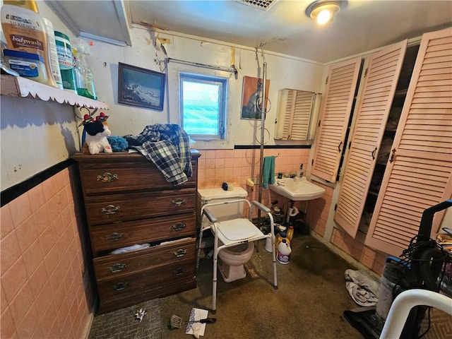 interior space featuring a wainscoted wall, a sink, and tile walls