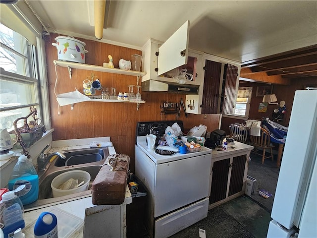 kitchen with wood walls, stove, a sink, and freestanding refrigerator