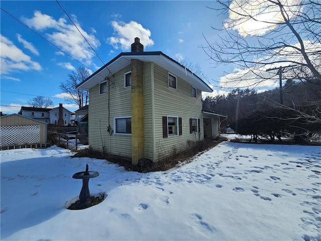 snow covered property with a chimney