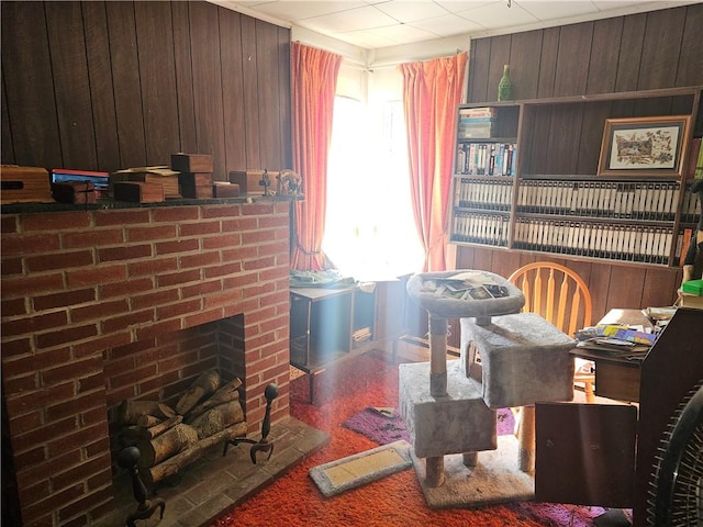 sitting room featuring wood walls and a brick fireplace