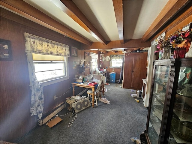 carpeted office space with beam ceiling and wood walls