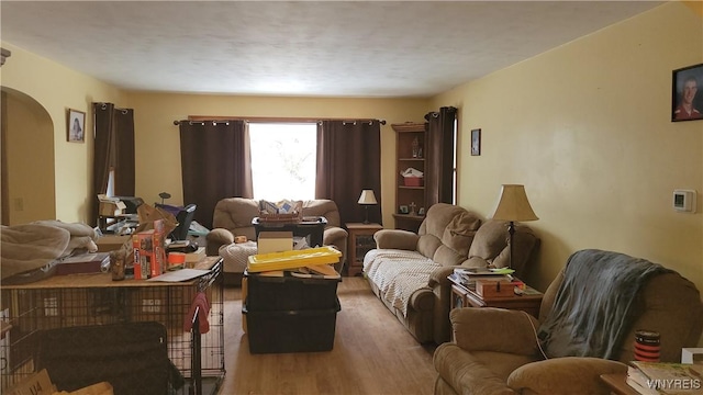 living area with light wood-style floors and arched walkways