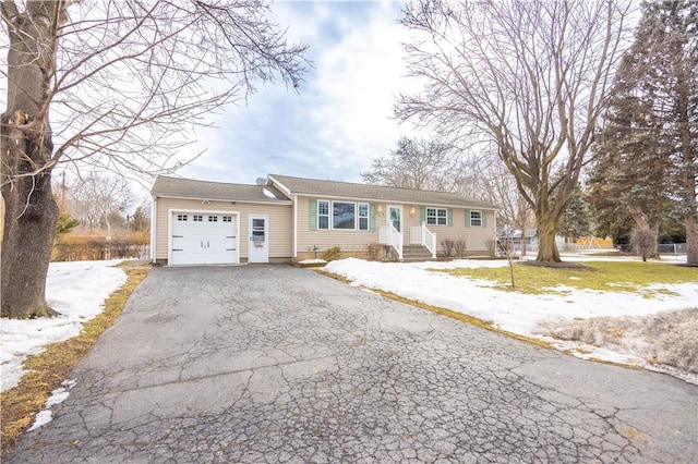 ranch-style home with a garage and aphalt driveway