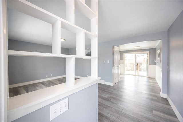 hallway featuring wood finished floors and baseboards