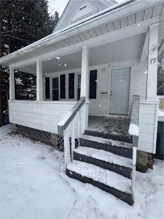 snow covered property entrance featuring a porch