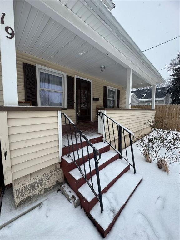 snow covered property entrance with a porch