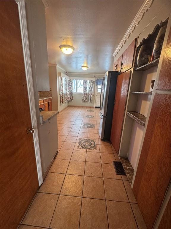 kitchen with visible vents, light tile patterned flooring, and freestanding refrigerator