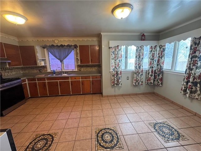 kitchen with light tile patterned floors, a sink, decorative backsplash, gas stove, and crown molding