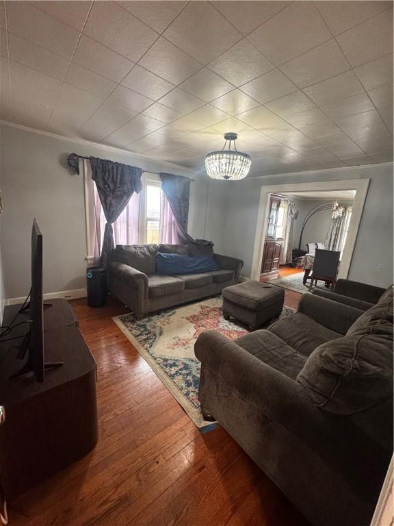 living area with ornamental molding, wood finished floors, and baseboards