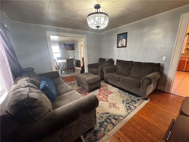 living room with an inviting chandelier, crown molding, and wood finished floors