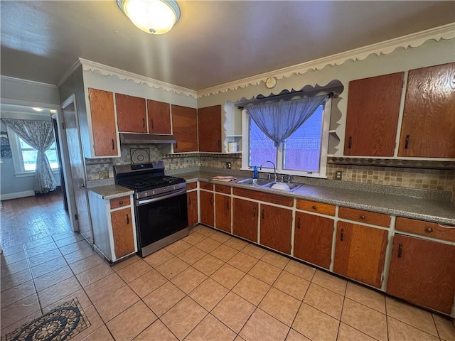 kitchen with stainless steel gas stove, under cabinet range hood, decorative backsplash, and a sink