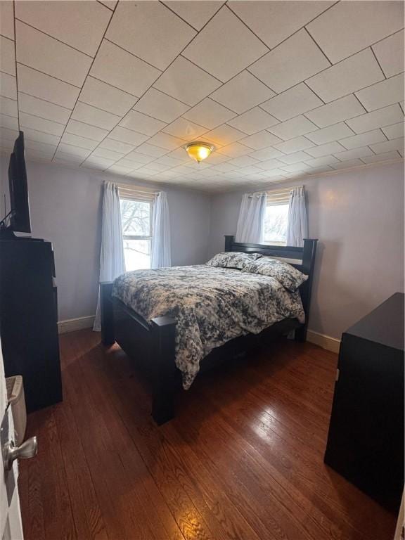 bedroom featuring dark wood-style flooring, multiple windows, and baseboards