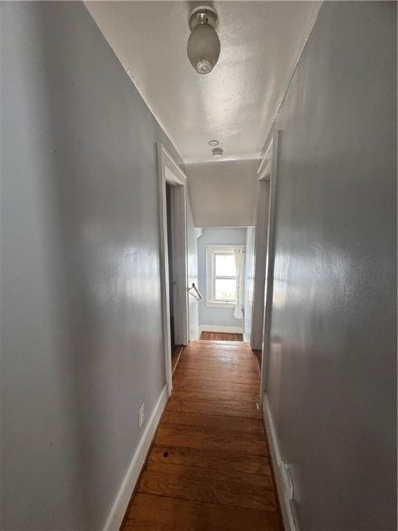 hallway with wood finished floors and baseboards