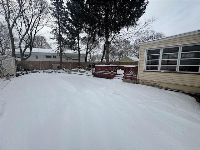 yard covered in snow featuring fence and a wooden deck