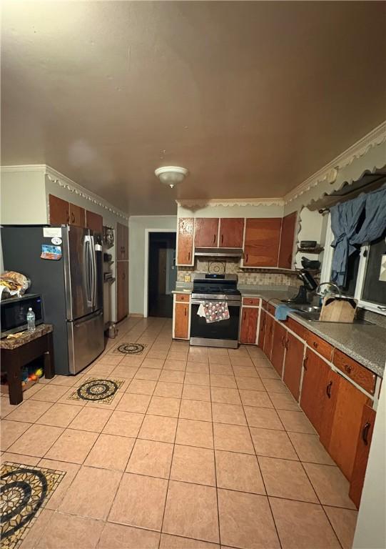 kitchen featuring crown molding, stainless steel appliances, backsplash, light tile patterned flooring, and under cabinet range hood